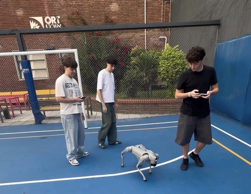 Tres estudiantes en el patio de ORT controlando un perro robot Unitree Go2